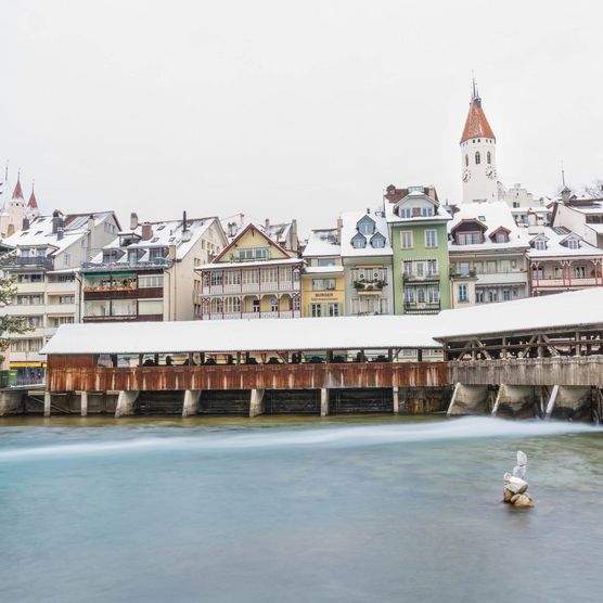 Verschneite Brücke über die untere Schleuse mit Kirche und Altstadt von Thun im Hintergrund