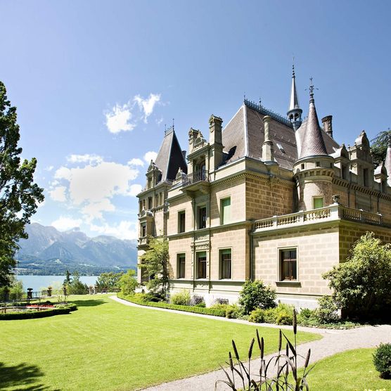 Schloss Hüngee in Hilterfingen mit grüner Wiese und Thunersee im Hintergrund