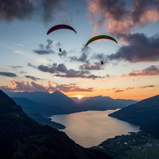 Paraglider an einem Herbstabend bei Sonnenuntergang in luftiger Höhe oberhalb von Interlaken