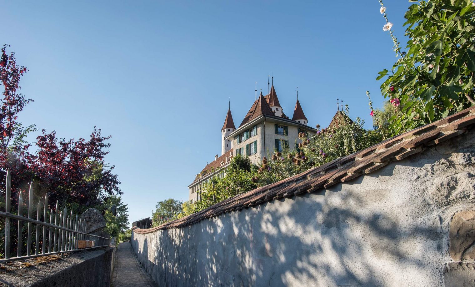 Der Aufstieg führt über Treppen hinauf zum Schlossberg, wo das Schloss Thun in der strahlenden Sonne thront