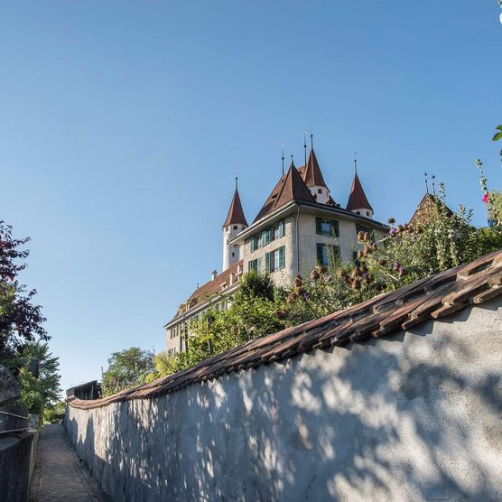 Der Aufstieg führt über Treppen hinauf zum Schlossberg, wo das Schloss Thun in der strahlenden Sonne thront