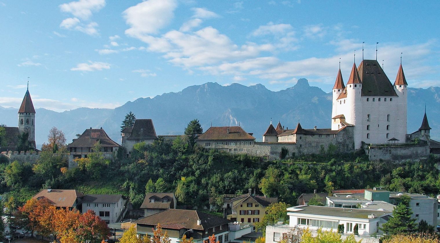 Der Schlossberg mit dem weissen Schloss Thun und der Schlosskirche sowie die Berge im Hintergrund