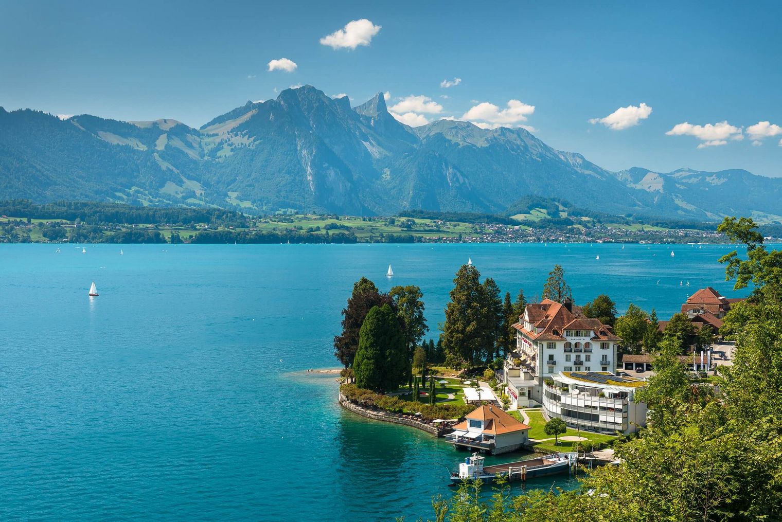 Luftaufnahme vom Parkhotel Gunten mit Thunersee und Berge