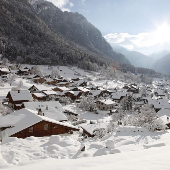 Verschneites Dorf Gsteigwiler mit Ausblick auf die winterliche Berglandschaft