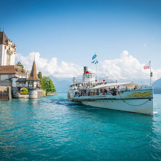 Märchenhaftes Schloss Oberhofen mit Dampfschiff Blümlisalp, das über den Thunersee gleitet. Im Hintergrund der Niesen.